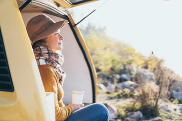 Young blonde Caucasian woman relaxing in her campervan at sunset