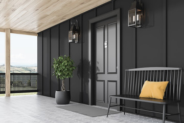Black front door of black house, bench, side view