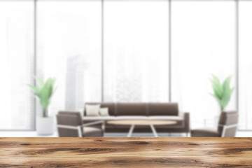 Table in blur office waiting room with brown sofa