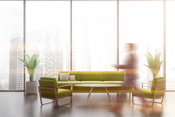 Man walking in panoramic lounge with green sofa