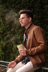 Fototapeta premium A young guy smokes, releases smoke from his mouth.