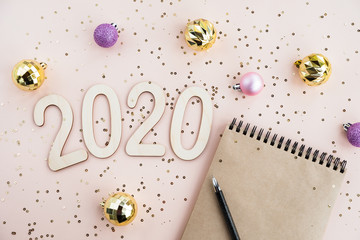 New year Goals Concept 2020. Notebook with blank sheet and festive decor. Stylish composition in light pink and gold colors. Top view, flat lay, copy space