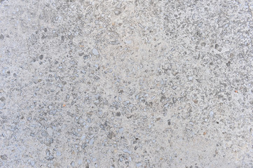 Gray concrete wall interspersed with small stones of natural rubble. Background