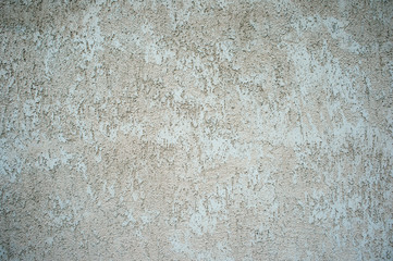 The wall of the building with a mottled surface of clay stucco gray beige shade. Background