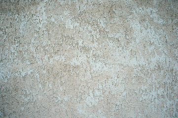 The wall of the building with a mottled surface of clay stucco gray beige shade. Background
