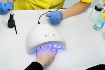 Nail care. Manicure in a manicure. the salon. Client's hand with varnish under a lamp for drying nails, LED lamp for nails