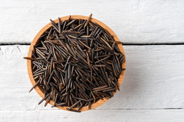 Wild rice in bowl on rustic wooden table. Top view