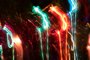 Fancy blurred glowing neon curls as flowing down on dark. Abstract luminous background. Long exposure while motion.