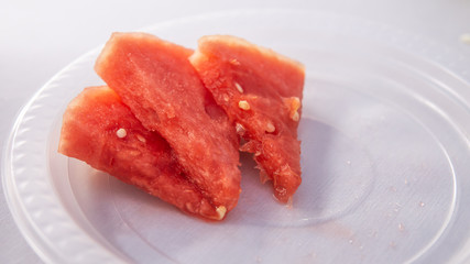 The close up view of the watermelon slices on a plastic plate with white backgrounds