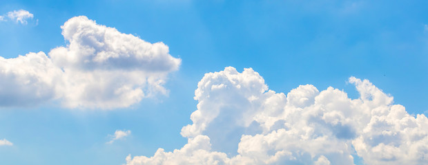 The white fluffy clouds and light blue sky in the sunny day. 
