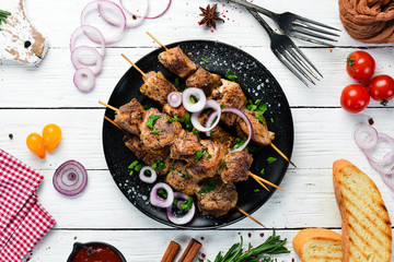 Juicy skewers of meat in a black plate. Barbecue, kebab. Top view. Free copy space.