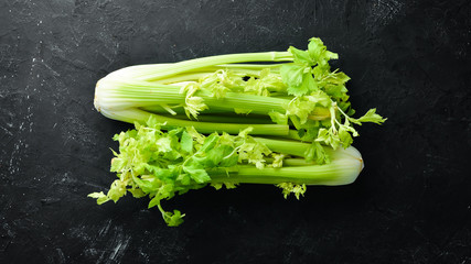 Fresh green celery stalk on a black background. Healthy food. Top view. Free space for your text.