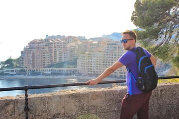 Fototapeta na wymiar Solo traveling man with backpack with Monaco city background 