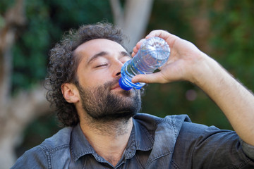 Portrait of man drinking water from a bottle outside. Healthy life concept