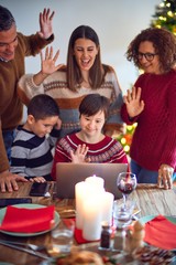 Beautiful family smiling happy and confident. Eating roasted turkey make videocall using laptop celebrating christmas at home