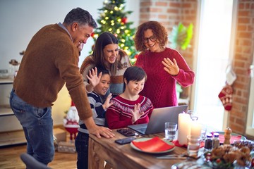 Beautiful family smiling happy and confident. Eating roasted turkey make videocall using laptop celebrating christmas at home
