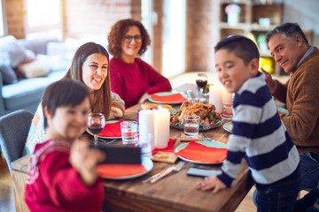 Beautiful family smiling happy and confident. Eating roasted turkey make selfie by smartphone celebrating christmas at home