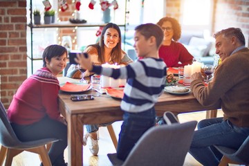Beautiful family smiling happy and confident. Eating roasted turkey make selfie by smartphone celebrating christmas at home