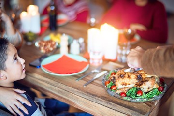 Beautiful family smiling happy and confident. One of them curving roasted turkey celebrating thanksgiving day at home