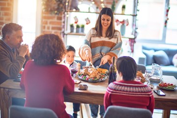 Beautiful family smiling happy and confident. One of them curving roasted turkey celebrating christmas at home