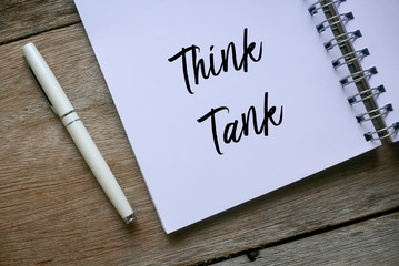 Top view of pen and notebook written with Think Tank on wooden background.