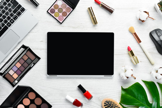 Female cosmetics on white office desk. Laptop, notepad, Lipstick, powder, comb, women's jewelry. Top view. Free space for your text. Flat lay.