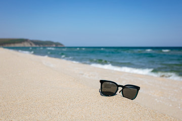 Fototapeta na wymiar Sunglasses on sandy beach, black sea