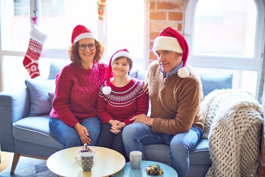 Beautiful family smiling happy and confident. Sitting on the sofa with smile on face wearing santa claus hat hugging around christmas decorations at home
