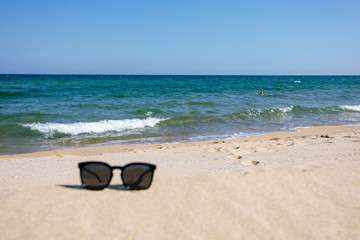 Sunglasses on sandy beach, black sea