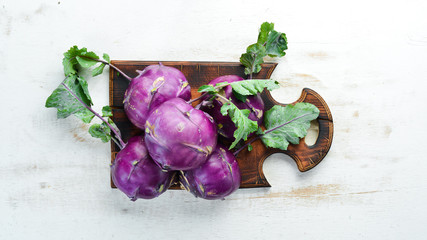 Kohlrabi cabbage with green leaves on wooden background. Top view. Free space for your text.