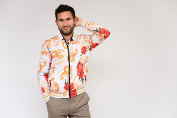 Men's fashion concept. Portrait of a handsome male model showing hands wearing a white floral jacket posing on a white background. Black hair. Close Studio Shot