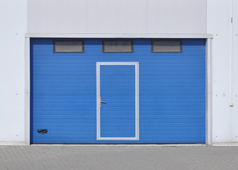 Obraz na płótnie Canvas Louvred gates of blue color at the entrance to the warehouse building.