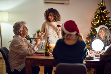 Beautiful group of women smiling happy and confident. On of them holding cup of wine speaking speech celebrating christmas at home