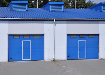 Louvred gates of blue color at the entrance to the warehouse building.
