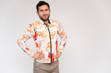 Men's fashion concept. Portrait of a handsome male model showing hands wearing a white floral jacket posing on a white background. Black hair. Close Studio Shot