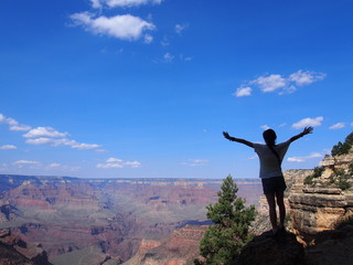 A man with her arms raised is impressed to see the spectacular view of the valley, Grand Canyon National Park, Arizona, USA