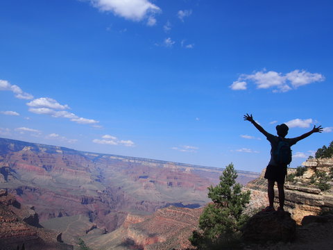 A man with her arms raised is impressed to see the spectacular view of the valley, Grand Canyon National Park, Arizona, USA