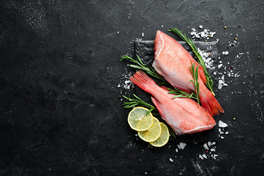 Fish raw snapper with lemon and rosemary. On a black background. Top view. Free space for your text.