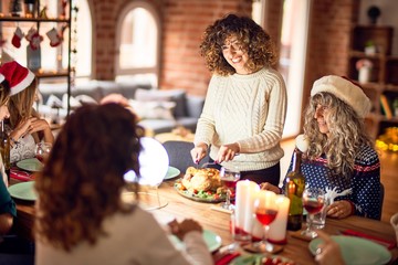 Beautiful group of women smiling happy and confident. Carving roasted turkey celebrating christmas at home