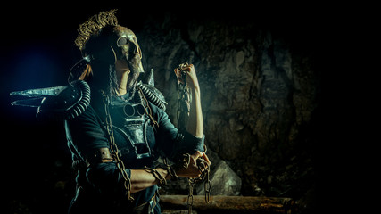 Post-apocalyptic woman in the rusty skull mask on the dungeon background. Nuclear post-apocalypse...