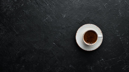 Cup of fragrant black coffee. On a black stone background. Top view. Free space for your text.