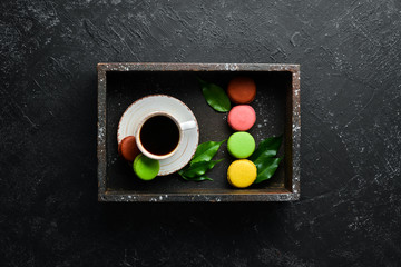 A cup of coffee with a macaroons cake. On a black stone background. Top view. Free space for your text.