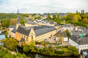 Fototapeta na wymiar Alzette river bend with Saint Jean Du Grund cathedral and row of the houses behind, Luxembourg city, Luxembourg