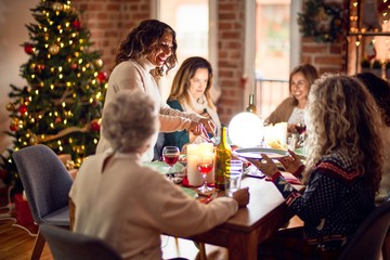 Beautiful group of women smiling happy and confident. Carving roasted turkey celebrating christmas at home