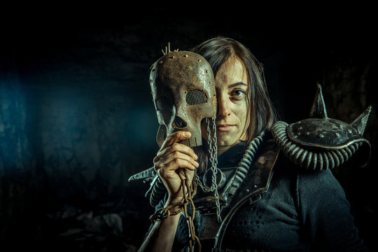 Post-apocalyptic woman in the rusty skull mask on the dungeon background. Nuclear post-apocalypse time. Life after doomsday