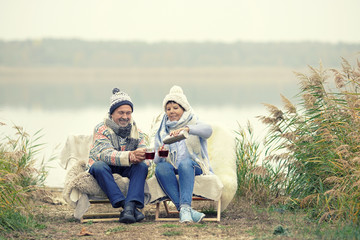 freudiges Paar im Winter am See - Glühwein trinken