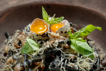 A plate of delicious pasta with bacon, cheese and quail egg.