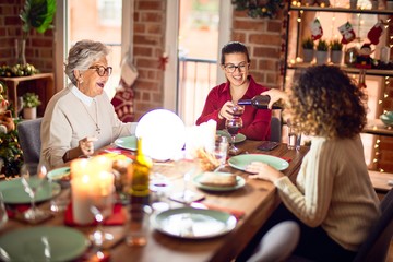 Beautiful group of women smiling happy and confident. Eating roasted turkey and serving wine on cup celebrating christmas at home