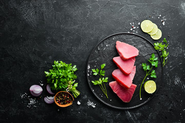 Obraz na płótnie Canvas Raw tuna fillet. Seafood on a black stone background. Top view. Free copy space.