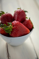 bowl of strawberries on a white wooden table